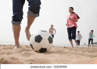 Young Friends Playing Soccer On The Beach