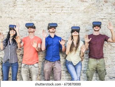 Young friends playing with virtual reality glasses outdoor - Young people having fun with new technology vr headset - Main focus on goggles glasses- New generation digital mania trends - Retro filter