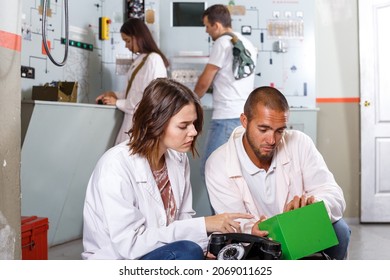 Young friends solving conundrum in quest room in view as closed nuclear bunker, inspecting battery charger - Powered by Shutterstock