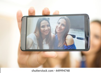 Young Friends Taking Selfie With Smart Phone Camera At Home. Close Up.