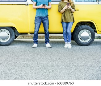 Young friends using mobile cell phones next minivan on urban street - Travel people addiction to new technology trends - Focus on hands smartphones - Warm filter - Powered by Shutterstock