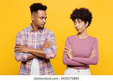 Young frowning couple two friends family man woman of African American ethnicity wear purple casual clothes together hold hands crossed folded look to each to other isolated on plain yellow background