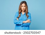 Young frowning indignant sad mad woman she wearing shirt casual clothes hold hands crossed folded looking camera isolated on plain pastel light blue cyan background studio portrait. Lifestyle concept