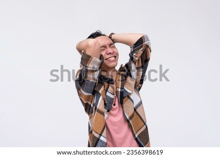 A young frustrated asian man venting out and breaking down from stress. Screwing up and overwhelmed by pressure. Mental health concept. Isolated on a white background.