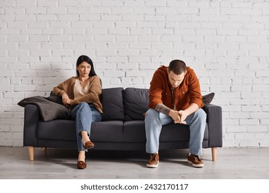 young frustrated interracial couple sitting on couch in living room, family divorce concept - Powered by Shutterstock