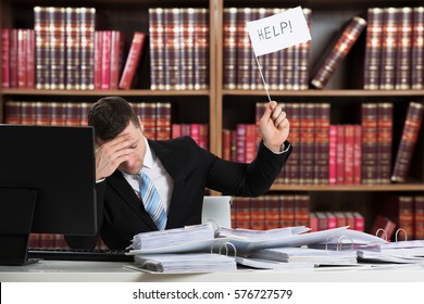 Young Frustrated Male Lawyer With A Load Of Work Holding Help Flag In A Courtroom