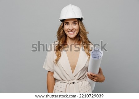 Young fun architect engineer designer employee white woman she wear pastel clothes hardhat hold blueprints isolated on plain light grey background studio portrait. People work on architecture project
