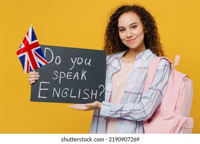 Young fun black teen girl student she wear casual clothes backpack bag hold british flag card sign do you speak english title text isolated on plain yellow background. High school university concept - Shutterstock ID 2190907269