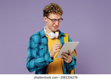 Young Fun Boy Teen Student In Casual Clothes Backpack Headphones Glasses Use Work On Tablet Pc Computer Isolated On Plain Violet Background Studio. Education In High School University College Concept