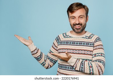 Young Fun Caucasian Man 30s He Wear Sweater Pointing Hands Arms Aside Indicate On Workspace Area Copy Space Mock Up Isolated On Plain Pastel Light Blue Cyan Background Studio. People Lifestyle Concept