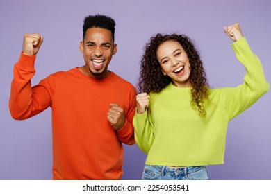 Young fun couple two friends family man woman of African American ethnicity wearing casual clothes together do winner gesture celebrate clenching fists isolated on pastel plain light purple background - Shutterstock ID 2254053541