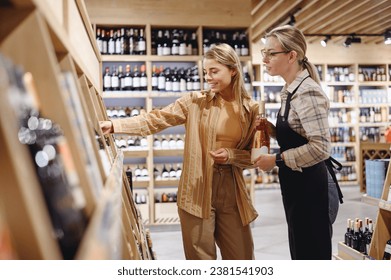 Young fun customer woman wear casual clothes chose wine bottle talk with seller sommelier shopping at supermaket store shop buy choose beverage products in hypermarket. Purchasing gastronomy concept - Powered by Shutterstock