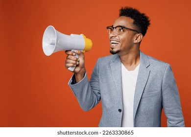 Young fun employee business man corporate lawyer wear formal grey suit shirt glasses work in office scream in megaphone announces discounts sale Hurry up isolated on plain red orange background studio - Powered by Shutterstock