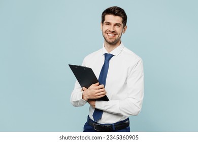 Young fun employee IT business man corporate lawyer wear classic formal shirt tie work in office hold clipboard with paper account documents isolated on plain pastel blue background studio portrait - Powered by Shutterstock