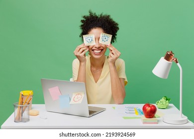 Young Fun Employee Business Woman Of African American Ethnicity In Shirt Sit Work At White Office Desk Pc Laptop Pretends To Work Hold Sticker Pattern Of Open Eyes Isolated On Plain Green Background