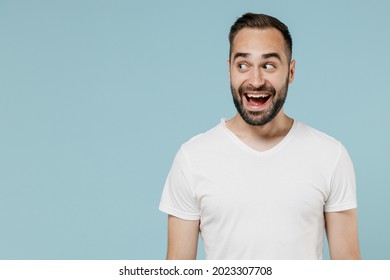 Young Fun Excited Amazed Surprised Happy Man 20s In Blank Print Design Casual White T-shirt Look Aside Isolated On Plain Pastel Light Blue Color Background Studio Portrait. People Lifestyle Concept