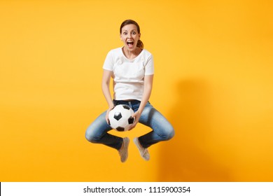 Young Fun Expressive European Woman Football Fan Jumping In Air, Cheer Up Support Team, Holding Soccer Ball Isolated On Yellow Background. Sport, Play Football, Cheer, Fans People Lifestyle Concept
