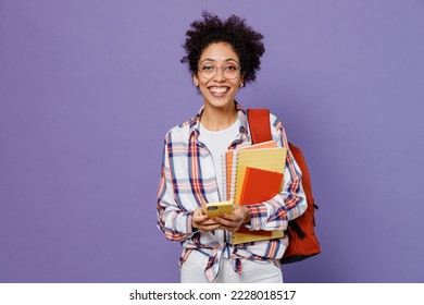 Young fun girl woman of African American ethnicity student in shirt backpack hold books use mobile cell phone isolated on plain purple background. Education in high school university college concept - Powered by Shutterstock