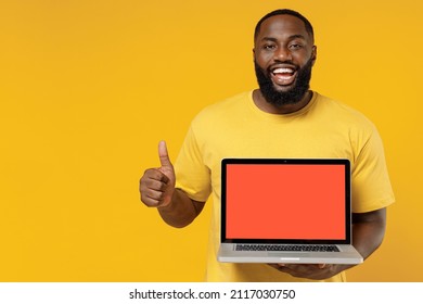 Young Fun Happy Black Man 20s Wearing Bright Casual T-shirt Hold Use Work On Laptop Pc Computer With Blank Screen Workspace Area Show Thumb Up Gesture Isolated On Plain Yellow Color Background Studio.