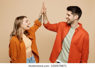 Young fun happy couple two friends family man woman wear casual clothes together meeting together greeting giving high five clapping hands folded isolated on pastel plain light beige color background