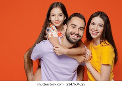 Young Fun Happy Parents Mom Dad With Child Kid Daughter Teen Girl In Basic T-shirts Giving Piggyback To Daughter Isolated On Yellow Background Studio Portrait. Family Day Parenthood Childhood Concept.