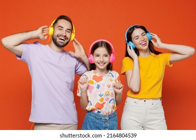 Young Fun Happy Parents Mom Dad With Child Kid Daughter Teen Girl In Basic T-shirts Headphones Listen To Music Isolated On Yellow Background Studio Portrait. Family Day Parenthood Childhood Concept.