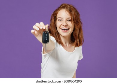 Young Fun Happy Satisfied Redhead Smiling Woman 20s Wear White Basic Casual T-shirt Giving Car Keys Fob Keyless System Show Thumb Up Gesture Isolated On Dark Violet Color Background Studio Portrait.