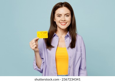 Young fun happy woman she wears purple shirt yellow t-shirt casual clothes hold in hand mock up of credit bank card isolated on plain pastel light blue background studio portrait. Lifestyle concept - Shutterstock ID 2367234341