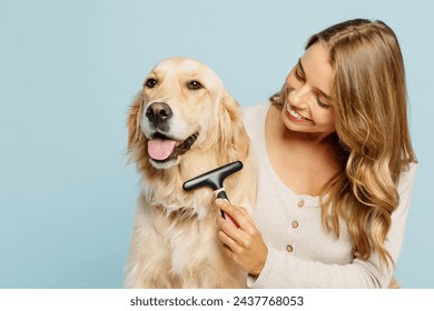 Young fun owner woman wear casual clothes hug cuddle best friend retriever dog hold grooming brush trimming isolated on plain pastel light blue background studio portrait. Take care about pet concept - Powered by Shutterstock