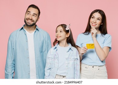 Young Fun Parents Mom Dad With Child Kid Daughter Teen Girl In Blue Clothes Hold In Hand Credit Bank Card Look Aside On Workspace Area Isolated On Plain Pastel Light Pink Background Family Day Concept