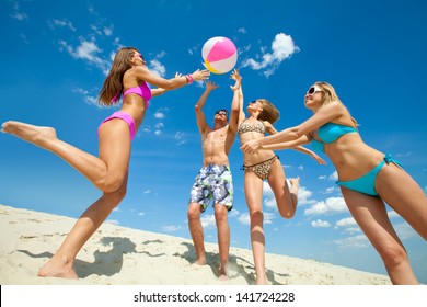 Young fun people are playing ball on the beach