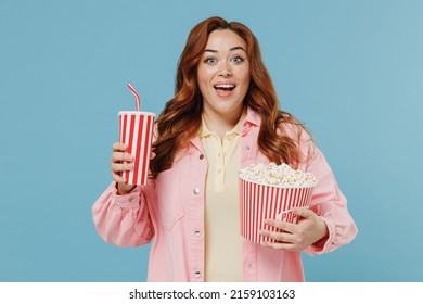 Young Fun Redhead Chubby Overweight Woman 30s Wearing Pink Shirt Casual Clothes Holding Takeaway Pop Corn Bucket Soda Cola Isolated On Pastel Blue Background Studio Portrait People Lifestyle Concept