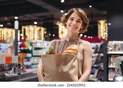 Young fun satisfied happy woman in casual clothes shopping at supermaket with craft paper package with groceries stand at store checkout inside hypermarket. People purchasing gastronomy food concept. - Powered by Shutterstock