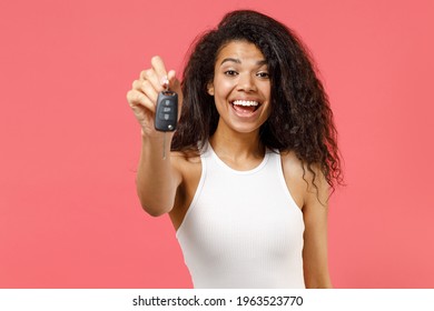 Young fun satisfied smiling happy african american woman 20s in casual white tank shirt giving car key fob keyless stystem look aside show thumb up gesture isolated on pink background studio portrait