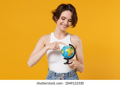 Young Fun Smiling Caucasian Geography Student Teacher Woman 20s Wearing White Tank Top Shirt Spin Touch Earth World Globe Isolated On Yellow Color Background Studio Portrait. People Lifestyle Concept