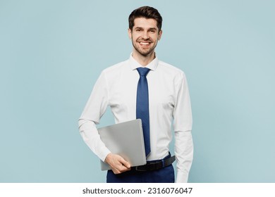 Young fun smiling employee IT business man corporate lawyer wear classic formal shirt tie work in office hold closed laptop pc computer isolated on plain pastel light blue background studio portrait