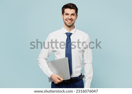 Young fun smiling employee IT business man corporate lawyer wear classic formal shirt tie work in office hold closed laptop pc computer isolated on plain pastel light blue background studio portrait