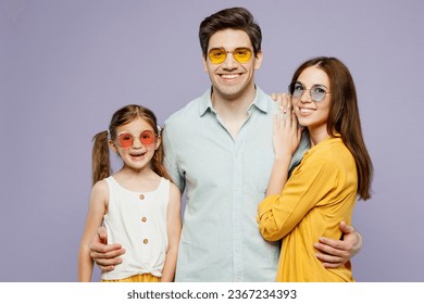 Young fun smiling happy parents mom dad with child kid daughter girl 6 years old wear blue yellow casual clothes sunglasses look camera hugging isolated on plain purple background. Family day concept - Shutterstock ID 2367234393