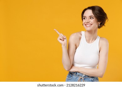 Young fun smiling happy woman 20s with bob haircut wearing white tank top shirt point index finger aside on workspace area mock up isolated on yellow color background studio People lifestyle concept. - Powered by Shutterstock