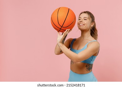 Young Fun Strong Sporty Athletic Fitness Trainer Instructor Woman Wear Blue Tracksuit Spend Time In Home Gym Throw Basketball Ball Isolated On Pastel Plain Light Pink Background. Workout Sport Concept