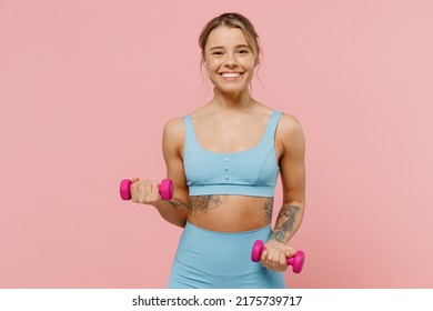 Young fun strong sporty athletic fitness trainer instructor woman wear blue tracksuit spend time in home gym hold female dumbbells isolated on pastel plain light pink background. Workout sport concept - Powered by Shutterstock