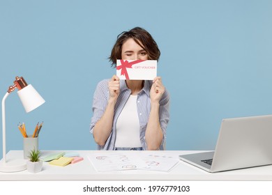 Young Fun Successful Employee Business Woman In Casual Shirt Sit Work At White Office Desk With Pc Laptop Hiding Cobver Mouth With Gift Voucher Flyer Mock Up Isolated On Pastel Blue Background Studio