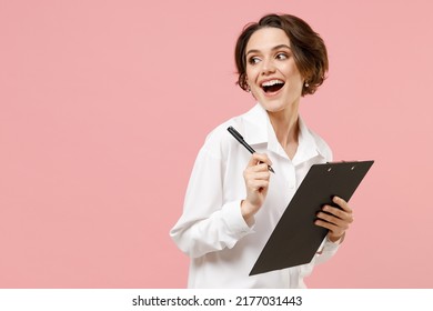 Young fun successful employee business secretary woman corporate lawyer in classic formal white shirt work in office clipboard with papers write document look aside isolated on pastel pink background - Shutterstock ID 2177031443