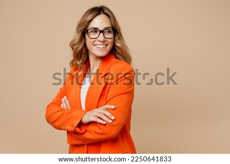 Young fun successful employee business woman corporate lawyer 30s wear classic formal orange suit glasses work in office look aside on workspace area mock up isolated on plain beige background studio