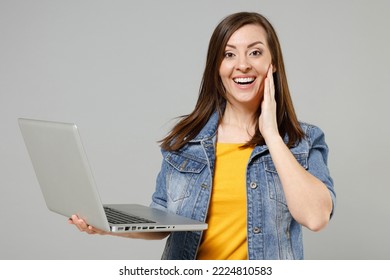Young fun surprised caucasian woman 20s wearing casual trendy denim jacket yellow t-shirt point index finger on laptop pc computer browsing hold face isolated on grey color background studio portrait - Shutterstock ID 2224810583