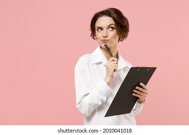 Young Fun Thoughtful Successful Employee Business Secretary Woman Corporate Lawyer In Classic Formal White Shirt Work In Office Clipboard With Papers Write Document Isolated On Pastel Pink Background