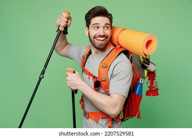 Young fun traveler white man carry backpack stuff hold trakking poles isolated on plain green background Tourist lead active healthy lifestyle walk on spare time Hiking trek rest travel trip concept