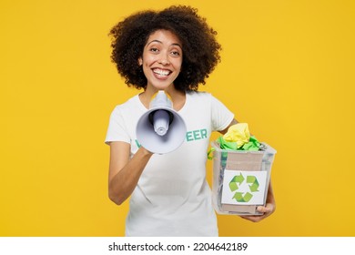 Young Fun Woman Of African American Ethnicity Wearing White Volunteer T-shirt Hold Boxes Waste Sorting Shout In Megaphone Isolated On Plain Yellow Background. Voluntary Free Work Help Grace Concept