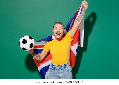 Young fun woman fan wear yellow t-shirt cheer up support football sport team hold in hand big British flag soccer ball watch tv live stream do winner gesture isolated on dark green background studio - Powered by Shutterstock