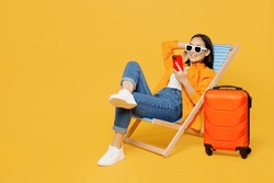 Young Fun Woman Wear Summer Clothes Sit In Deckchair Use Mobile Cell Phone Isolated On Plain Yellow Background. Tourist Travel Abroad In Free Spare Time Rest Getaway. Air Flight Trip Journey Concept